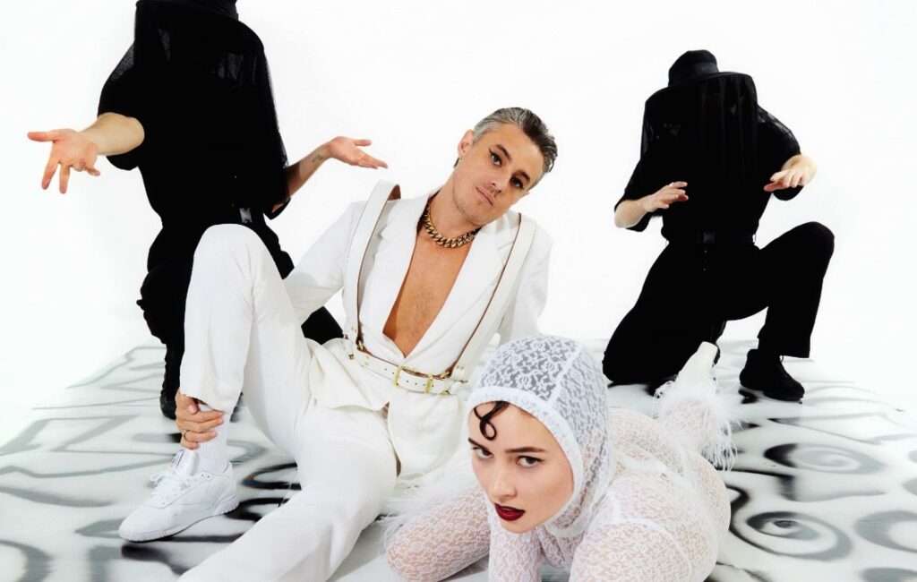 Confidence Man pose in white suits in a press photo