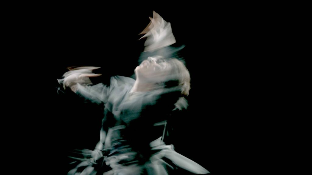Blurred image of a man dancing against a black backdrop
