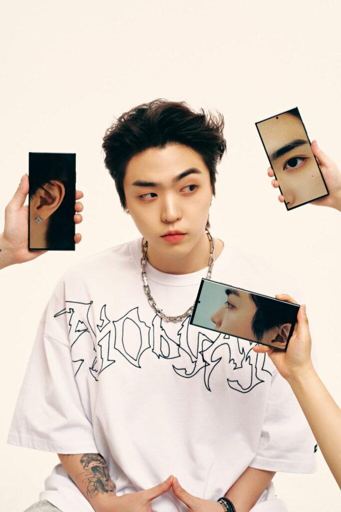 JUNNY with photos of his face on phone screens being held up around him