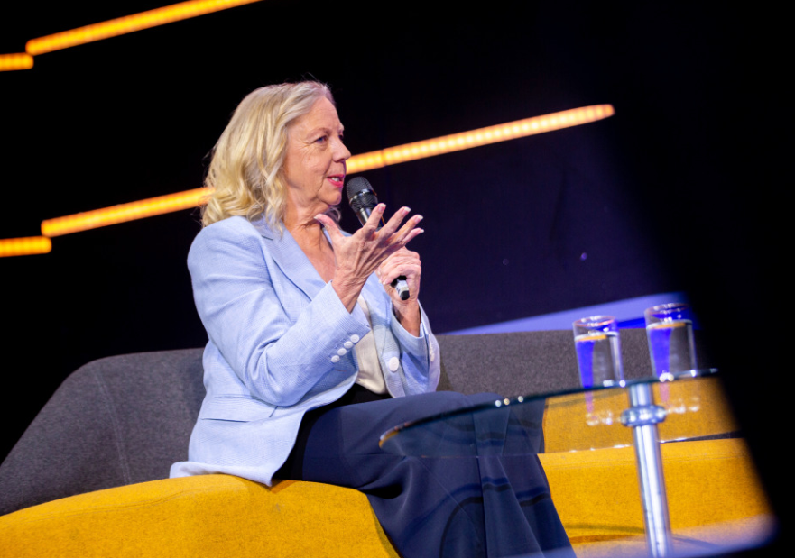 Deborah Meaden sitting on a yellow couch onstage