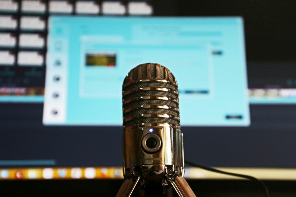 Stock image of a podcast mic in front of a PC monitor