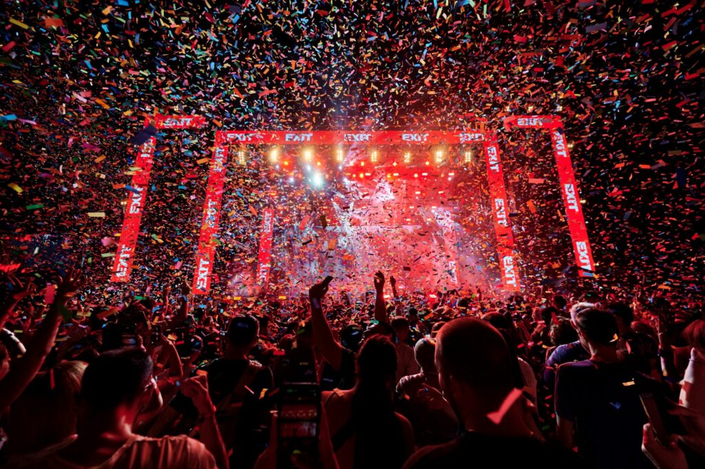 A festival stage showing fireworks and dancing people