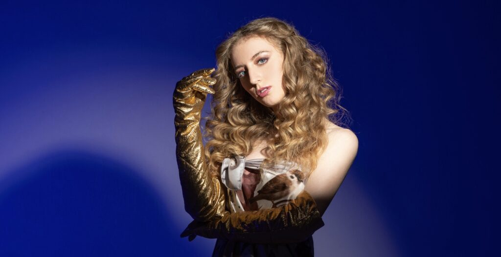 A woman poses against a blue backdrop