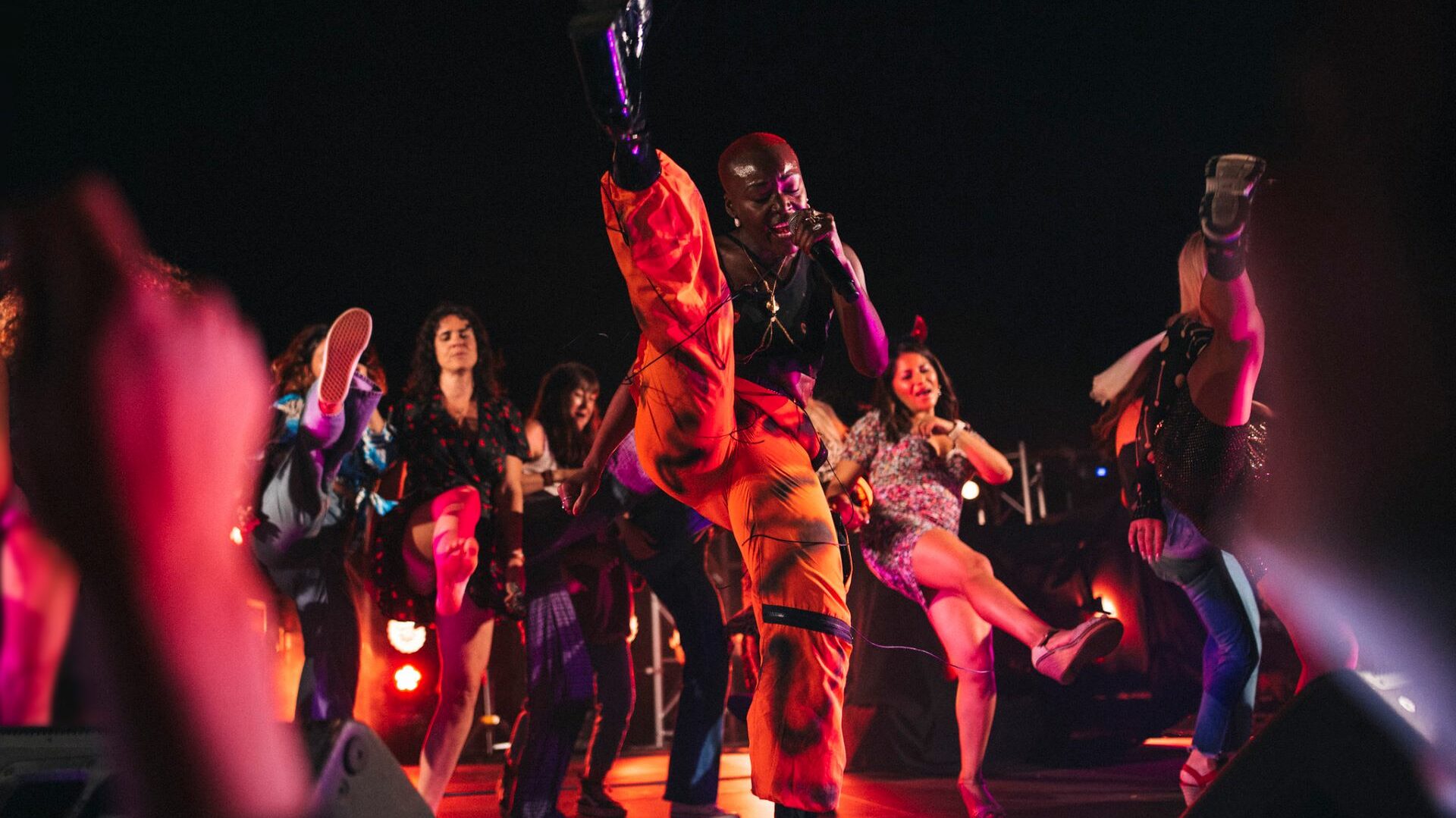 People on a dance stage with a person doing a high-kick in the centre