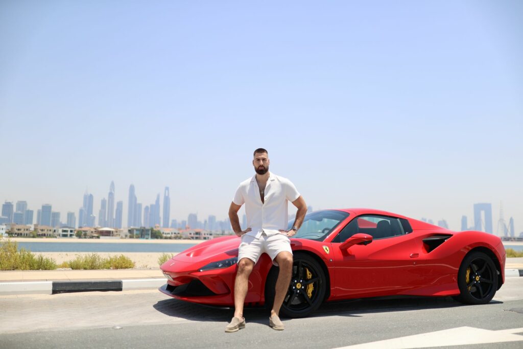 A man leaning on a red sports car