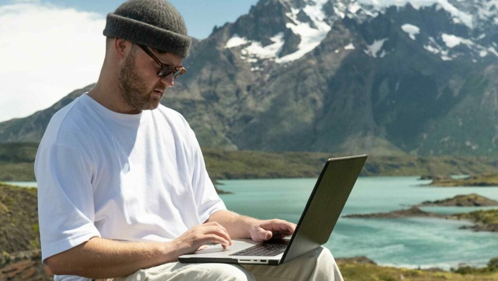 A man working on a laptop by a mountain