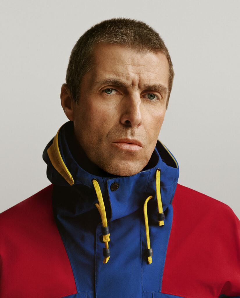 Liam Gallagher wears blue and red Berghaus jacket with yellow details