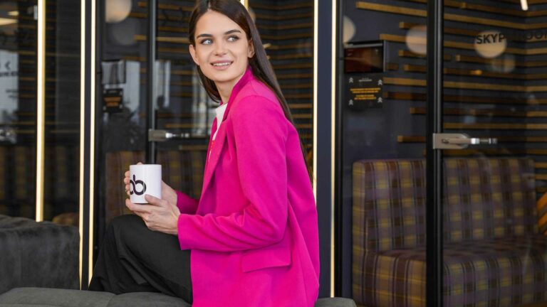 A woman in a pink blazer holding a mug