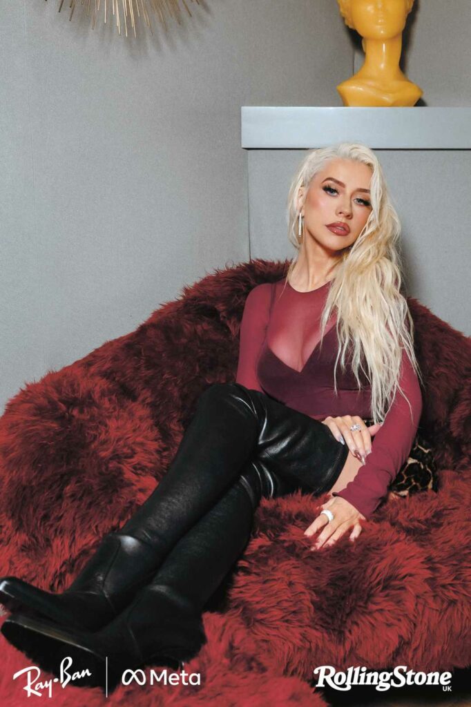 Christina Aguilera sitting on a red couch