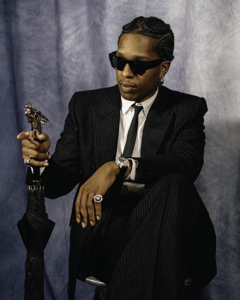 A$AP Rocky poses in black Ray-ban sunglasses in pinstripe black suit, white shirt, black tie